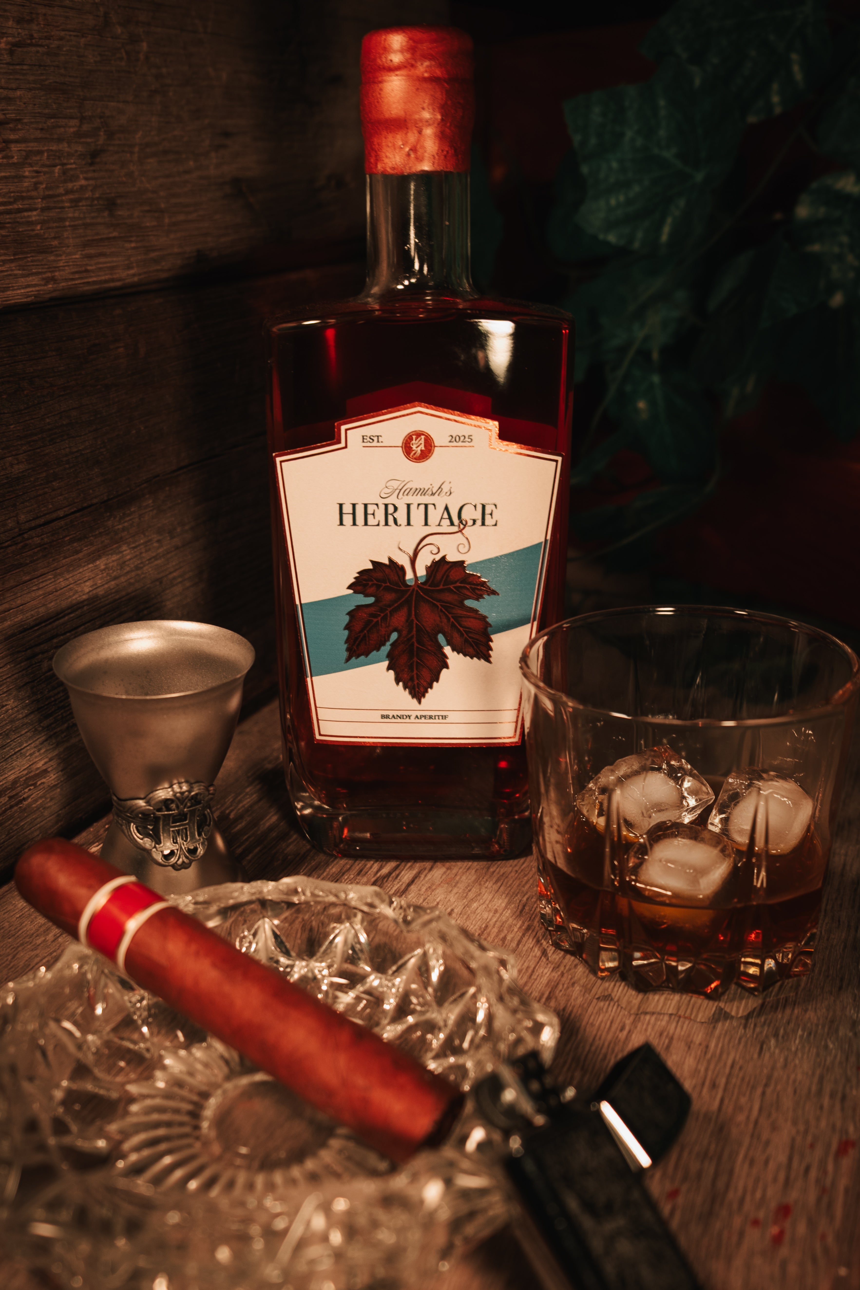 Bottle of Heritage brandy from Hamish's Liquor with a glass and cigar on a wooden surface.